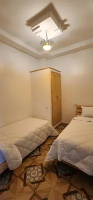 a bedroom with two beds and a chandelier at الراحة والسلامة مراكش in El Gouassem