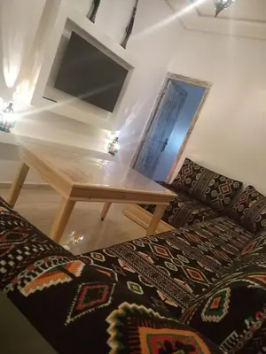 a living room with a wooden table and a television at الراحة والسلامة مراكش in El Gouassem