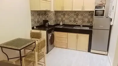 a kitchen with a refrigerator and a table in it at الراحة والسلامة مراكش in El Gouassem
