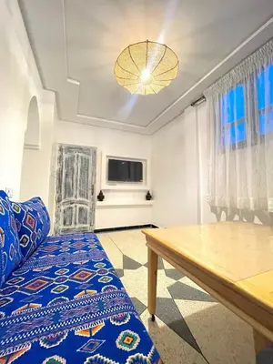 a living room with a blue bed and a wooden table at Modern et calme a Marrakech in Marrakech