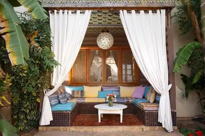 a patio with a couch and a table and curtains at Daba Riads in Marrakech