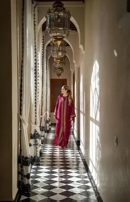 a woman walking down a hallway in a building at Daba Riads in Marrakech