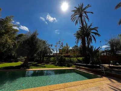a swimming pool in a yard with palm trees at Villa kasbah de luxe, piscine et jacuzzi chauffés, jardin tropical in Marrakech
