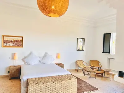 a bedroom with a bed and chairs and a chandelier at Villa Zaria Marrakech Heated Pool Family Friendly 25 Min To Medina in Marrakech