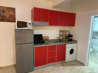 a kitchen with red cabinets and a washing machine at l'évasion 8 face gare CTM Hivernage a 10mn de l'aéroport in Marrakech