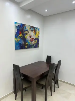 a dining room table with chairs and a painting on the wall at Séjour haut de gamme lit king TV cinéma 65 in Marrakech