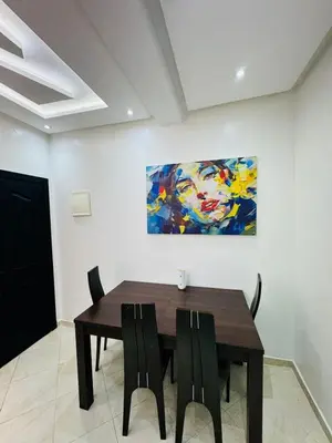 a dining room with a table and a painting on the wall at Séjour haut de gamme lit king TV cinéma 65 in Marrakech