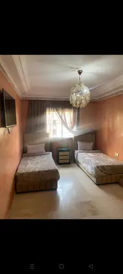 a bedroom with two beds and a chandelier at Riad jawhara in Marrakech