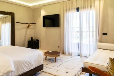 a bedroom with a bed and a couch and a television at Suite avec vue époustouflante sur les jardins majorelle in Marrakech