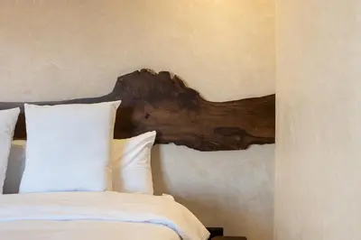 a bed with a wooden headboard and white pillows at Suite avec vue époustouflante sur les jardins majorelle in Marrakech