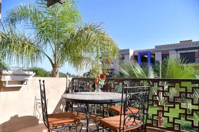 a table and chairs with a vase on a patio at Ideal family apartment in Marrakech