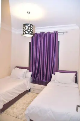 two beds in a room with a purple curtain at Ideal family apartment in Marrakech