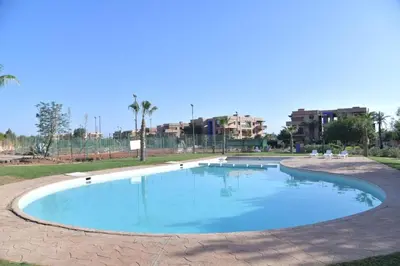 an empty pool in a park with buildings in the background at Ideal family apartment in Marrakech