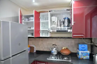 a kitchen with red cabinets and a white refrigerator at Ideal family apartment in Marrakech