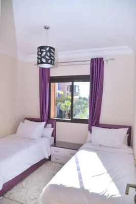 two beds in a room with a window at Ideal family apartment in Marrakech