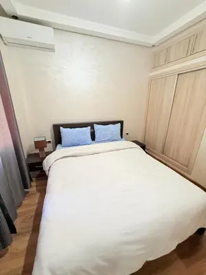 a bedroom with a large white bed with blue pillows at Appartement N15 Lumineux Calme & Centre-ville in Marrakech