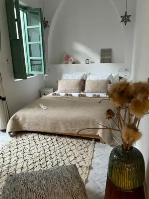 a bedroom with a bed and a vase with flowers at Riad Les 3J in Marrakech