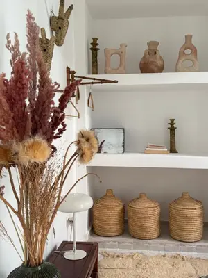 a shelf with baskets and a vase with flowers at Riad Les 3J in Marrakech