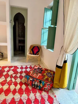 a room with a rug on the floor and a chair at Riad Les 3J in Marrakech