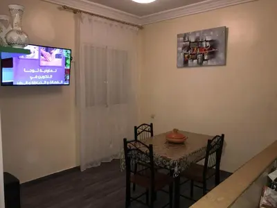 a dining room with a table and a television at Appartement Simouni in Marrakech