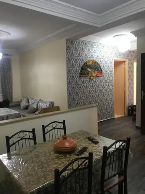 a dining room with a table and chairs and a bed at Appartement Simouni in Marrakech