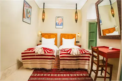two beds in a room with a table and a mirror at Riad Dar Dounia in Marrakech