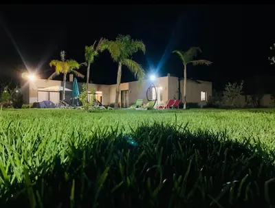 a house with palm trees and a lawn at night at villa abraj in Marrakech