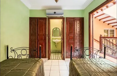 two beds in a room with a bathroom at Riad Golden Palm in Marrakech