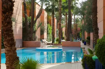 a courtyard with palm trees and a swimming pool at Riad Golden Palm in Marrakech