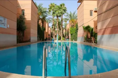 a swimming pool in the middle of a building with palm trees at Riad Golden Palm in Marrakech