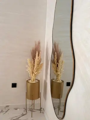 a mirror on a wall with two vases with feathers at Apartment JADE Palmeraie, residence with pool in Marrakech