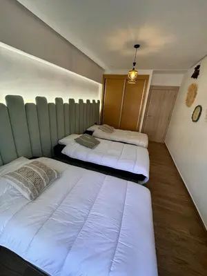 a room with two beds in a room with a wall at Apartment JADE Palmeraie, residence with pool in Marrakech
