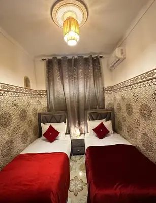 two beds with red pillows in a room at Apartment in heart of Medina in Marrakech