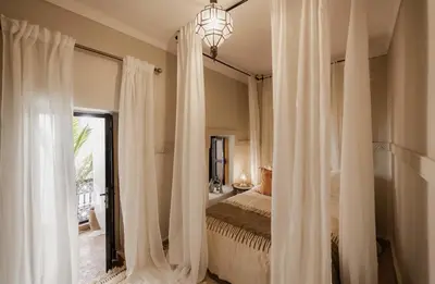 a bedroom with white curtains and a bed and a window at Riad Privatif avec Personnel et Services Exclusifs - Kasbah Boma Marrakech I in Marrakech