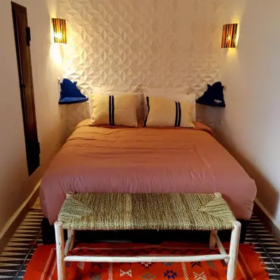 a bedroom with a bed with a bench in it at Riad bab Adam in Marrakech