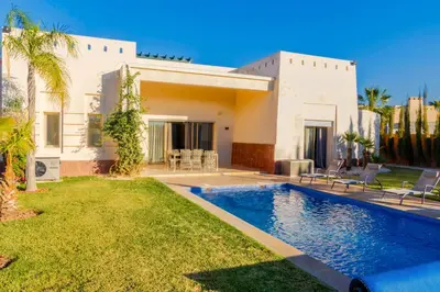 a villa with a swimming pool in front of a house at Heated Pool Villa in Marrakech