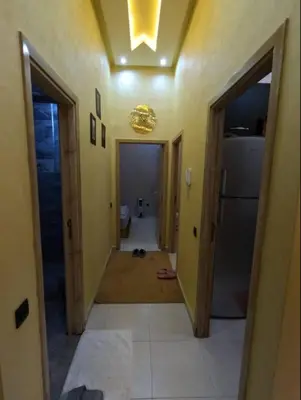 a hallway leading to a kitchen with a refrigerator at Appartement en résidence in Marrakech