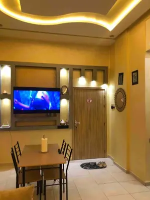 a dining room with a table and a tv on the wall at Appartement en résidence in Marrakech