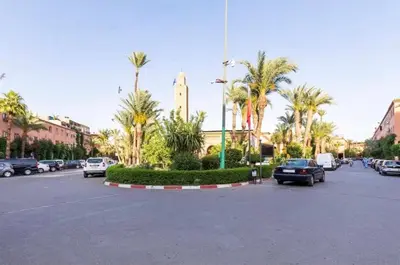 a parking lot with palm trees and a clock tower at Blue Room in Marrakech
