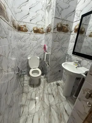 a white bathroom with a toilet and a sink at شقة بمدينة مراكش بقرب جميع المرافق in Marrakech