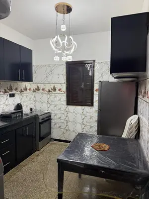 a kitchen with black cabinets and a table with a pizza on it at شقة بمدينة مراكش بقرب جميع المرافق in Marrakech
