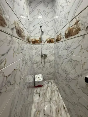a white marble bathroom with a shower and a sink at شقة بمدينة مراكش بقرب جميع المرافق in Marrakech