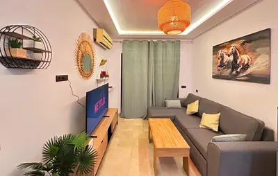 a living room with a couch and a tv at Le Coup de cœur de Guéliz avec Piscine et Parking in Marrakech