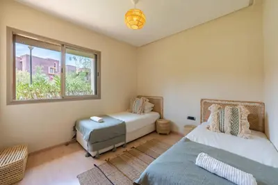 a bedroom with two beds and a window at Trois chambres et Jardin Prive a Prestigia in Marrakech