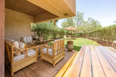 a patio with two chairs and a table and an umbrella at Trois chambres et Jardin Prive a Prestigia in Marrakech