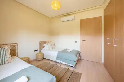 a bedroom with two beds and a sliding door at Trois chambres et Jardin Prive a Prestigia in Marrakech