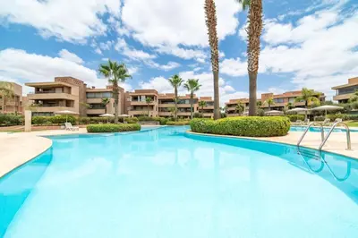 a large swimming pool with palm trees and condos at Trois chambres et Jardin Prive a Prestigia in Marrakech