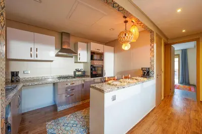 a large kitchen with white cabinets and wooden floors at Spacious Luxury Apartment with Heated Pool Center in Marrakech