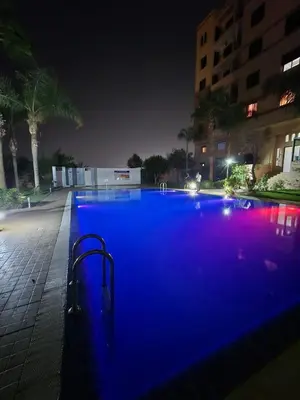 a large swimming pool at night with blue illumination at Séjour Familial à Marrakech in Marrakech