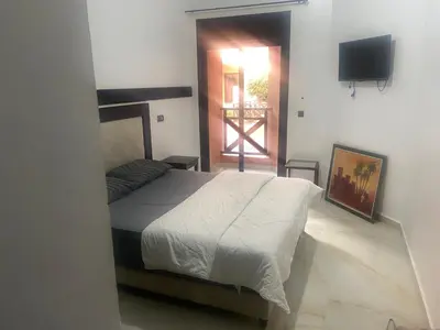 a bedroom with a bed and a television and a door at Cosy appartement avec piscine in Marrakech